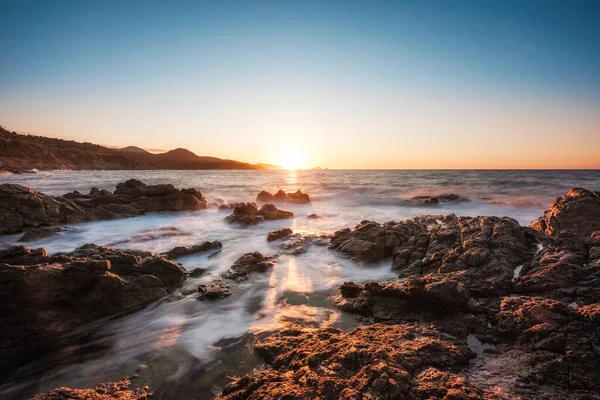 太陽がイル ルセのBalagne町に沈むとコルシカ島の岩の海岸線に洗濯波の長い露出イメージ — ストック写真