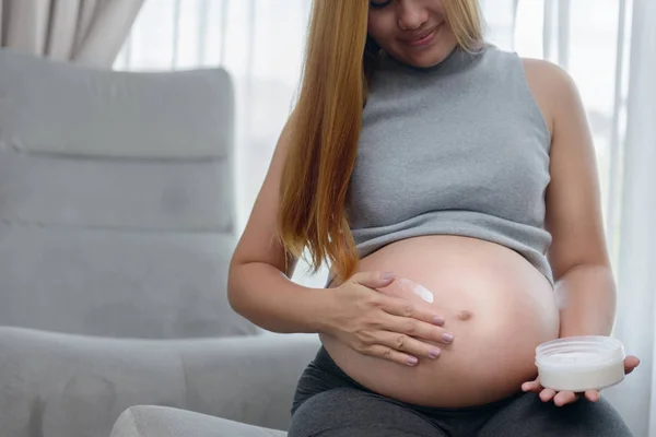 Mulher grávida aplicando creme em sua barriga — Fotografia de Stock