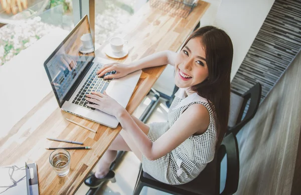 Charmig kvinna med vackert leende arbetar på laptop under vila i kafé — Stockfoto