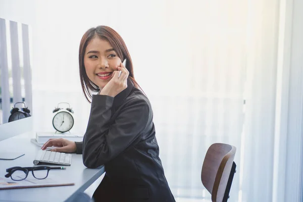 Donna d'affari che utilizza il cellulare e il computer in ufficio . — Foto Stock