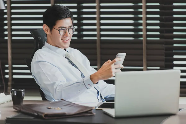 Hombre de negocios asiático usando smartphone en la oficina — Foto de Stock