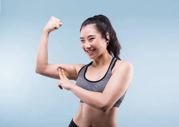 Allegramente sorridente asiatica donna sportiva dimostrando bicipiti — Foto Stock