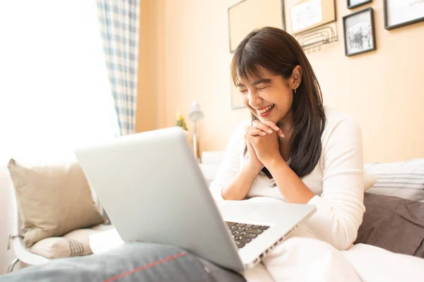 집에서 프리랜서로 침대에 앉아서 노트북으로 일하는 평범하고 아름다운 여성이 — 스톡 사진