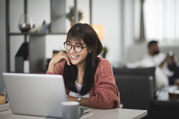 在笔记本电脑上工作的快乐而随意的美丽的亚洲女人 作为一个自由职业者坐在桌子上 从家里的概念开始工作 — 图库照片