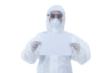 Koruyucu elbiseli bir doktor beyaz arka planda boş bir kağıt tutuyor..