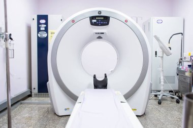 Radyoloji odasındaki tomografi makinesi beyaz arkaplanda.