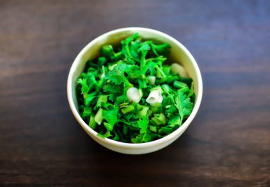 Bir kase doğranmış taze soğan. Ahşap arka planda izole edilmiş. Üst manzara.