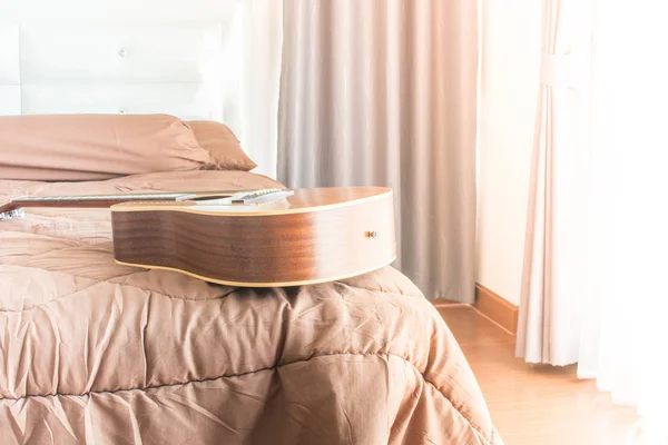 image of bed room in day time,guitar placed on the bed and  laminate floor