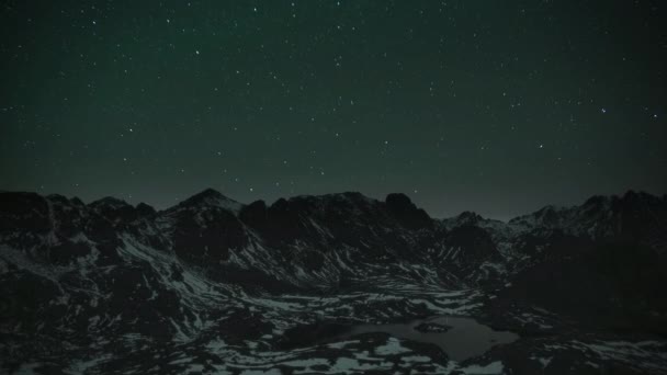 Résolution 8K 76804320 30p. Spectaculaire vue de nuit depuis le sommet de la montagne. Étoiles dans le ciel nocturne à haute altitude montagnes enneigées. La lumière des étoiles se reflète sur la surface du lac dans la montagne. Lac glaciaire en hiver froid .