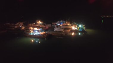 Balıkçı gemilerinden kargo kamyonlarına yükleme. Limandaki gemilerin ışıkları altında çalışan balıkçılar. Balıkçılık endüstrisi için ideal, gece işi hayatı. İşçiler gece yarısı liman limanında hareket edebilirler. Deniz piyadesi okyanus havası limanına demir atmışlardır..