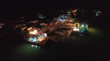 Balıkçı gemilerinden kargo kamyonlarına yükleme. Limandaki gemilerin ışıkları altında çalışan balıkçılar. Balıkçılık endüstrisi için ideal, gece işi hayatı. İşçiler gece yarısı liman limanında hareket edebilirler. Deniz piyadesi okyanus havası limanına demir atmışlardır..