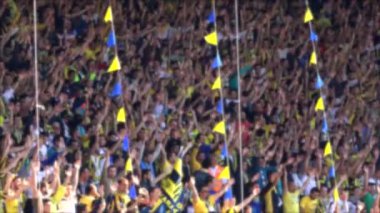 Heyecanlı ve mutlu taraftarlar sarılmak, stadyumda neşe içinde dans etmek. Kalabalık tezahürat yapıyordu. Tribünde tezahürat yap. Futbol takımı izleyicileri. Grup müziği, şarkı söyleyen alkış alkışları. Futbol maçı destekçisi. Holigan holiganlık taraftarı kalabalık gol sesi çıkarıyor