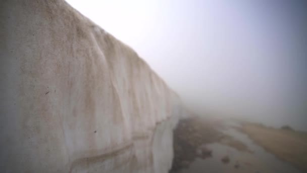 山道の側に雪の壁 厚い氷の雪の層ブロック ダーティ ほこりっぽい 泥だらけの古い茶色の雪 雲の中で汚れの方法 風景霧のために表示されません 標高の高い氷の寒い冬の氷の山の自然雲霧 — ストック動画