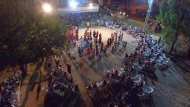 Bu gerçek bir etnik köy düğünü. Romanyalı çingenelerin dansları. Halay dansçıları bir çember ya da çizgi oluştururlar. Hatta göğüs göğüse. Geleneksel kına gecesi. Kırmızı gelinlikli gelin dans ediyor. Havadan insanlar dans ediyor. Alkışlıyorlar.