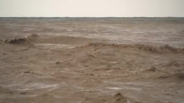 Kahverengi çamurlu deniz dalgaları. Sel suları denize ulaşır. Nehrin ağzında güçlü bir dalga oluşturur. Çamur yağmurdan sonra denize doğru ilerliyor. İnanılmaz hızlı akan azgın bir nehir okyanusu..