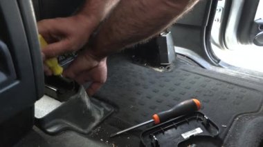 Araç koltuğunu söküyorum. Araba koltuğu yere sabitlendi. Bir işçi araba koltuğunu sökmeye çalışıyor. Profesyonel ana soket anahtarı ayarlı tornavida tornavida çalışıyor..