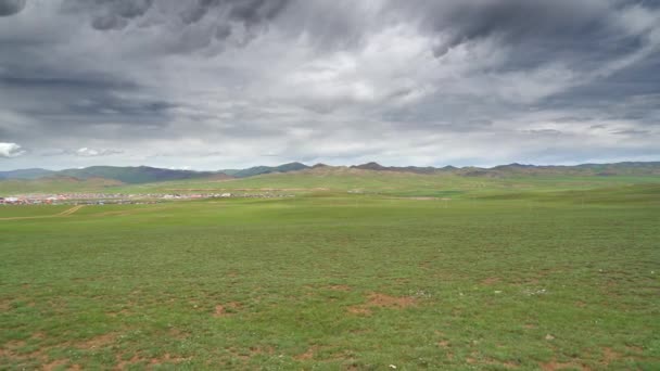 モンゴルの古典的な伝統的な都市のカラフルな屋根の家 家のフェンスで囲まれた庭園 広い平野には町の背後に丘がある 緑の牧草地を通過する未舗装の道路 4KだRkhon川 サイト 風景低地のステップ — ストック動画