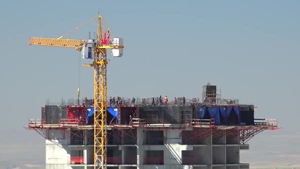 クレーンや建設労働者は 主要な作業 建物のサイト上のビルダー 超高層ビルで壁の型を運ぶ コンクリートと鉄の組み合わせ 材料を運ぶ黄色の色のクレーン 産業の強化バーフロアを鋳造 搭乗員 — ストック動画