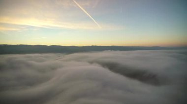 Sinema 8K 7680x4320. Sabah gökyüzünde standart gündoğumu bulutu hareketleri. Stratus 'tan bir sis denizi oluşur. Bulutların üstünde. Düz yüzey. Bulutlu, güneşli bir gün karışımı hızlandırılmış vasthill hava kaplı dağ sırtı fantastik harika