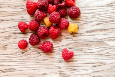 Masanın üstüne dağılmış ahududu böğürtlenleri. sarı ve kırmızı ahududu