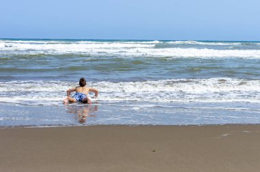 Çocuk sahilde bir gün geçirip deniz suyuyla oynuyor.