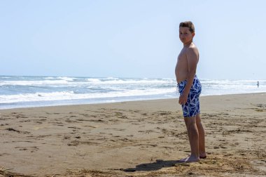 Çocuk sahilde bir gün geçirip deniz suyuyla oynuyor.