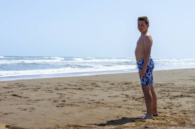 Çocuk sahilde bir gün geçirip deniz suyuyla oynuyor.