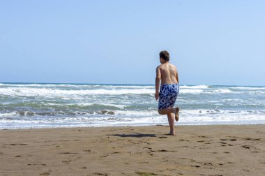 Çocuk sahilde bir gün geçirip deniz suyuyla oynuyor.