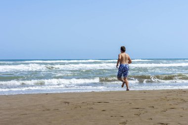Çocuk sahilde bir gün geçirip deniz suyuyla oynuyor.