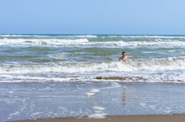 Çocuk sahilde bir gün geçirip deniz suyuyla oynuyor.