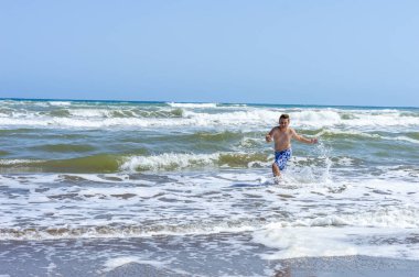 Çocuk sahilde bir gün geçirip deniz suyuyla oynuyor.