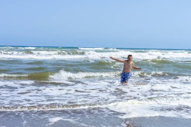 Çocuk sahilde bir gün geçirip deniz suyuyla oynuyor.