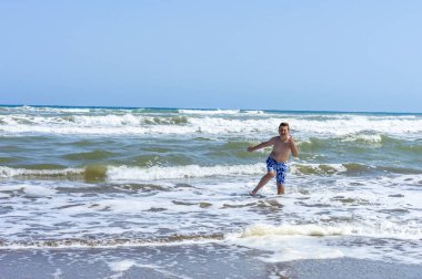 Çocuk sahilde bir gün geçirip deniz suyuyla oynuyor.