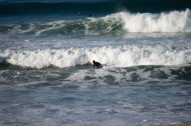 San Sebastian 'ın Zurriola plajında sörf tahtasıyla dalgaların üzerinde kayıyordu.