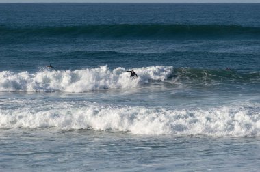 San Sebastian 'ın Zurriola plajında sörf tahtasıyla dalgaların üzerinde kayıyordu.