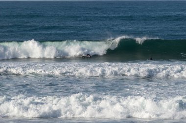 San Sebastian 'ın Zurriola plajında sörf tahtasıyla dalgaların üzerinde kayıyordu.