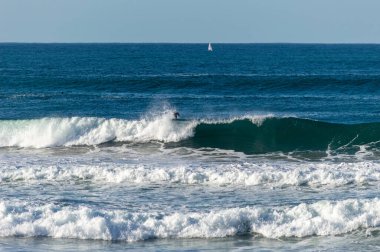 San Sebastian 'ın Zurriola plajında sörf tahtasıyla dalgaların üzerinde kayıyordu.