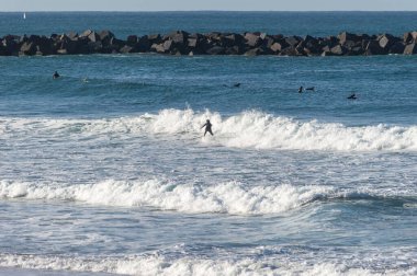 San Sebastian 'ın Zurriola plajında sörf tahtasıyla dalgaların üzerinde kayıyordu.