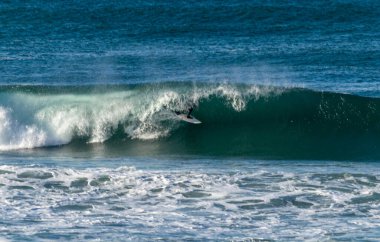 San Sebastian 'ın Zurriola plajında sörf tahtasıyla dalgaların üzerinde kayıyordu.