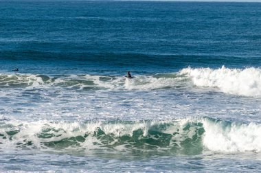 San Sebastian 'ın Zurriola plajında sörf tahtasıyla dalgaların üzerinde kayıyordu.
