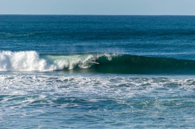 San Sebastian 'ın Zurriola plajında sörf tahtasıyla dalgaların üzerinde kayıyordu.