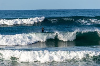 San Sebastian 'ın Zurriola plajında sörf tahtasıyla dalgaların üzerinde kayıyordu.