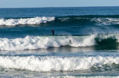 San Sebastian 'ın Zurriola plajında sörf tahtasıyla dalgaların üzerinde kayıyordu.