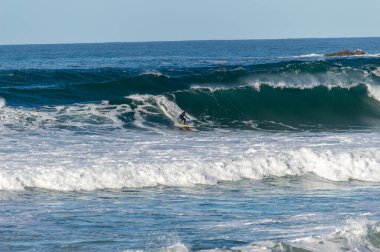 San Sebastian 'ın Zurriola plajında sörf tahtasıyla dalgaların üzerinde kayıyordu.