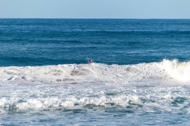 San Sebastian 'ın Zurriola plajında sörf tahtasıyla dalgaların üzerinde kayıyordu.
