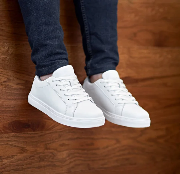 white casual shoes hanging down on the wooden background