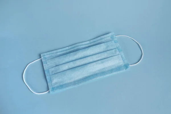 face mask isolated on blue background. piece of personal protection during covid pandemia. surgery mask, medical equipment