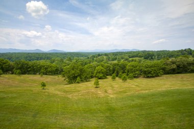 Taze biçilmiş çayırlarda orman ve uzak dağlar var.