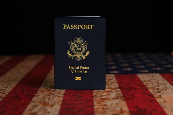 Passaporte dos EUA em pé na bandeira americana rústica com backgrou preto — Fotografia de Stock