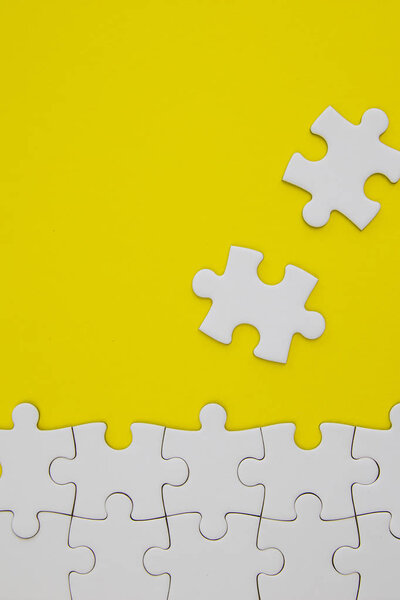 White jigsaw puzzle pieces on yellow background with negative sp